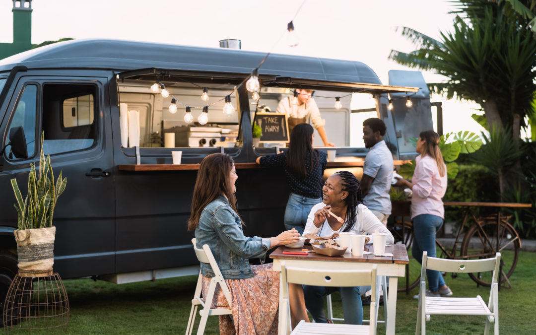 Two women sitting at a table in front of a coffee van 